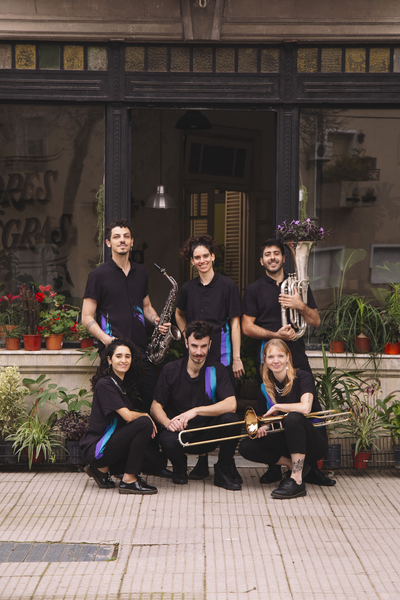 Desmadre Orkesta posing on the sidewalk with their instruments