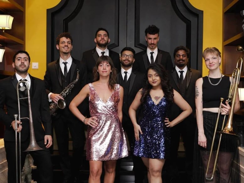 Desmadre XL in formal wear: musicians in suits and two singers in sequined dresses