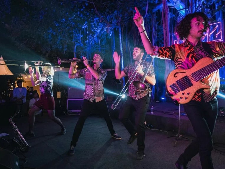 Desmadre XL playing outdoors at night, with trumpet, trombone and bass