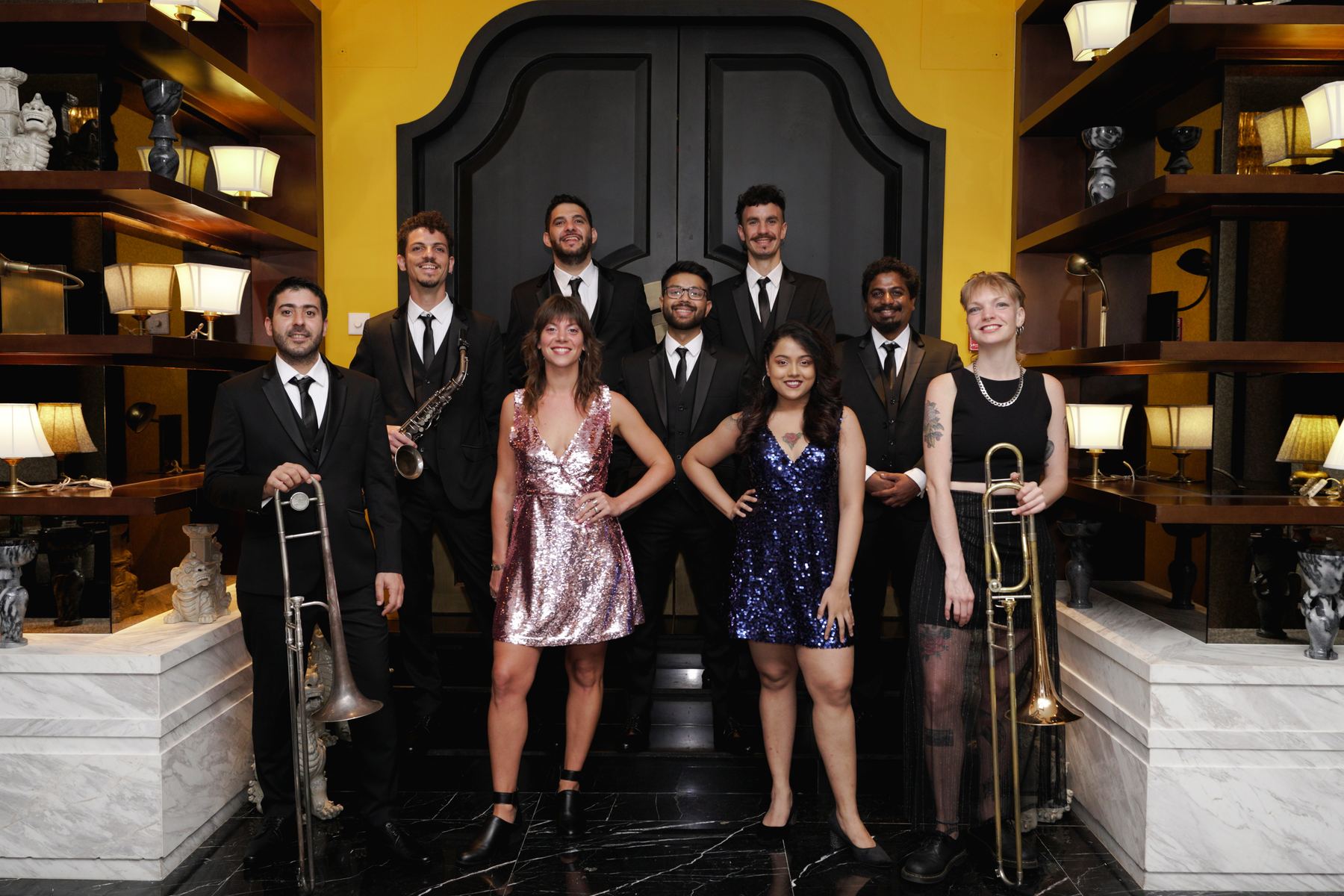Desmadre XL in formal wear: musicians in suits and two singers in sequined dresses